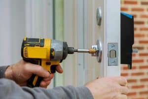 handyman-using-drill-installing-lock-door-house_optimized - My Local Locksmith drilling lock on door